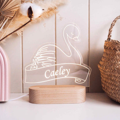 This is a swan night light with a personalised name "Caeley". It also has a wooden base